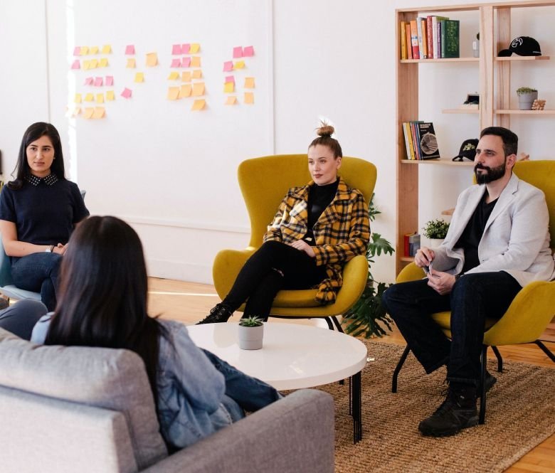 Team members sitting in a modern office space having a web design strategy discussion during a creative meeting.
