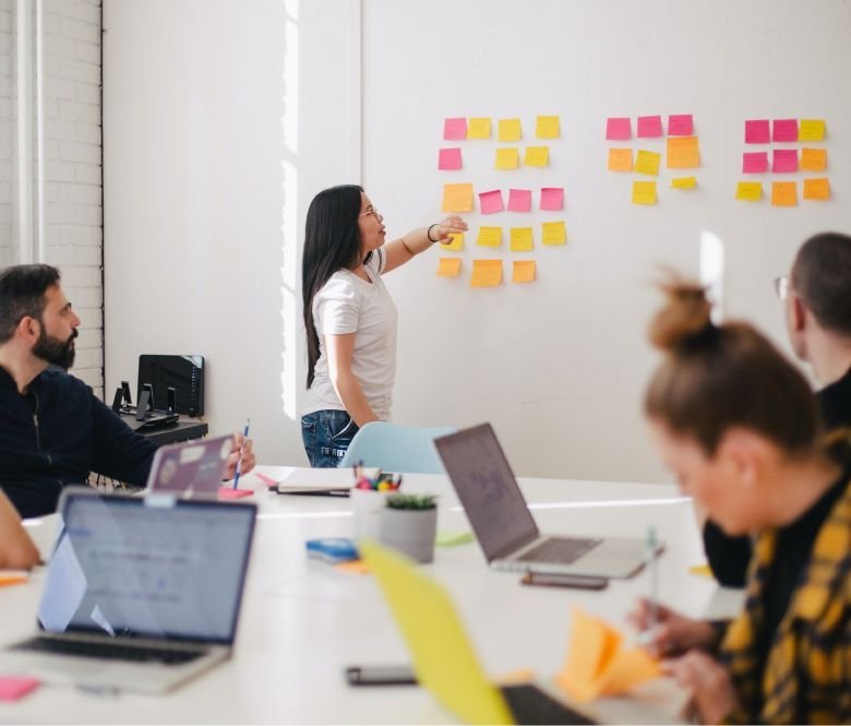 A creative team discussing web design ideas during a brainstorming session using sticky notes in an office.
